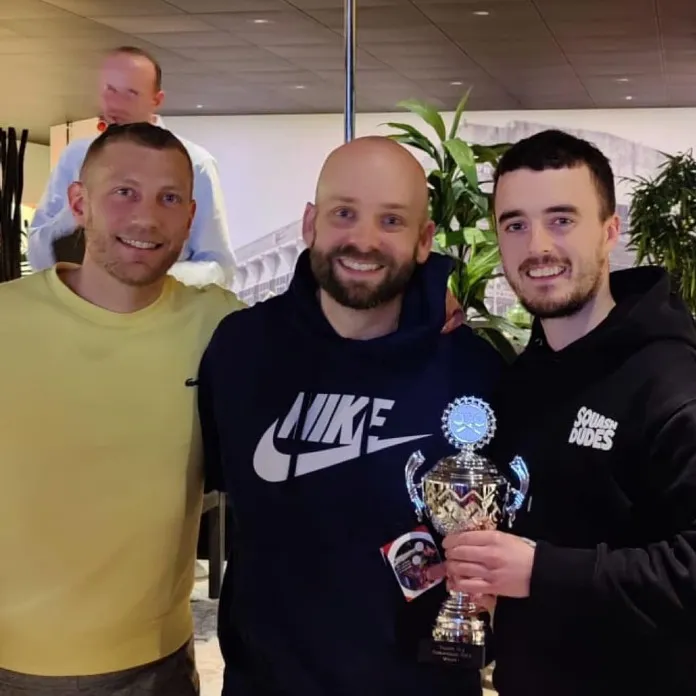 Three players holding a trophy and drinks after a club tournament