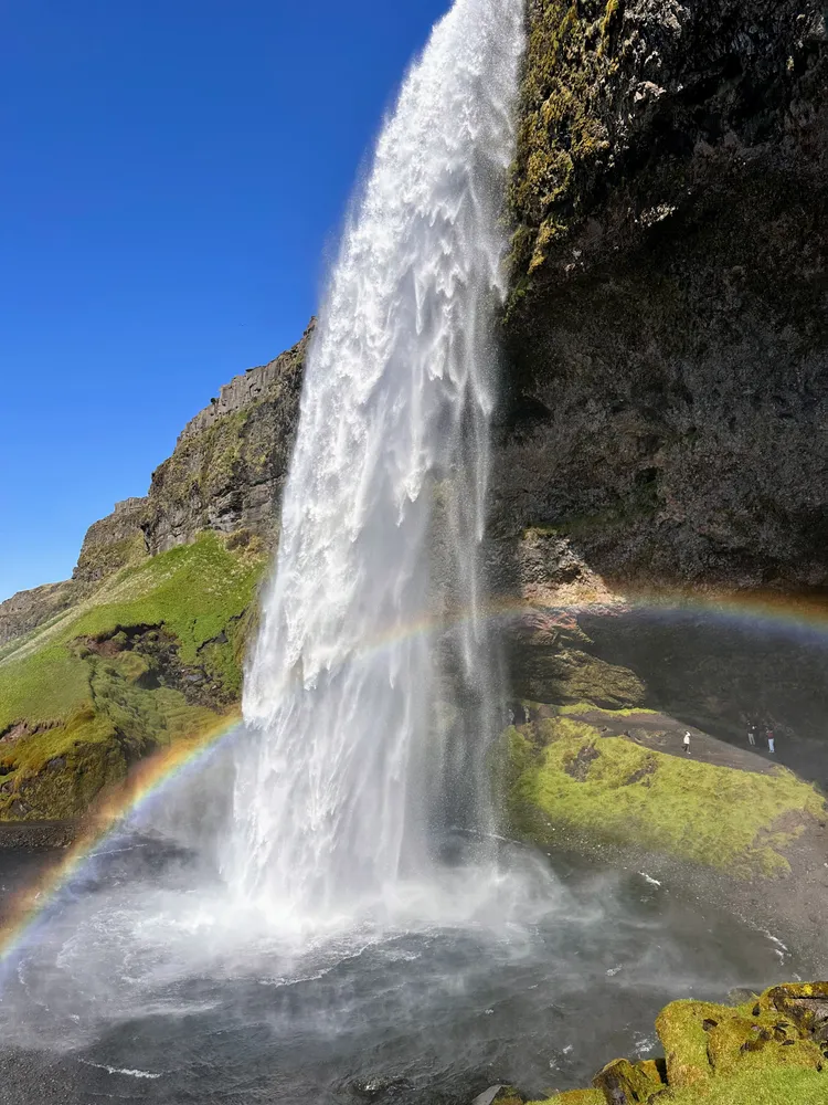 A waterfall pouring off a cliff with a rainbow arcing through the spray